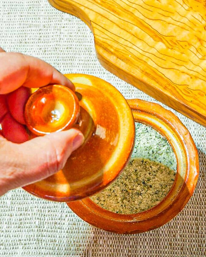 how to make herbed salt, person removing top on an orange ceramic salt keep of herb salt b