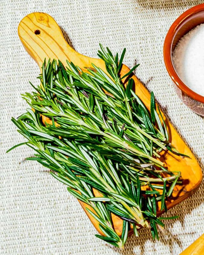how to make herbed salt, Ingredients for rosemary salt rosemary sprigs on a small cutting board next to a brown enamel cup of salt