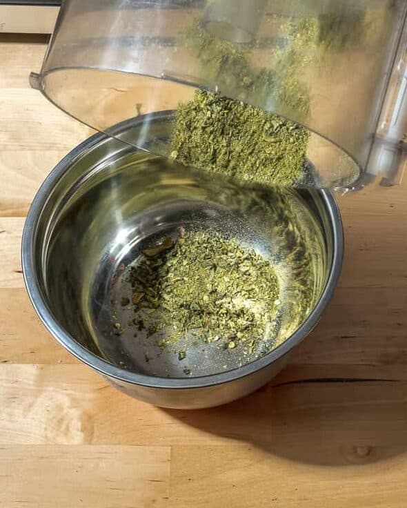 how to make herbed salt, person pouring dried pepper powder into small metal bowl