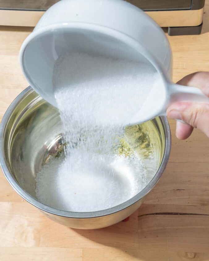 how to make herbed salt, person adding salt to small bowl with dried jalapeno powder
