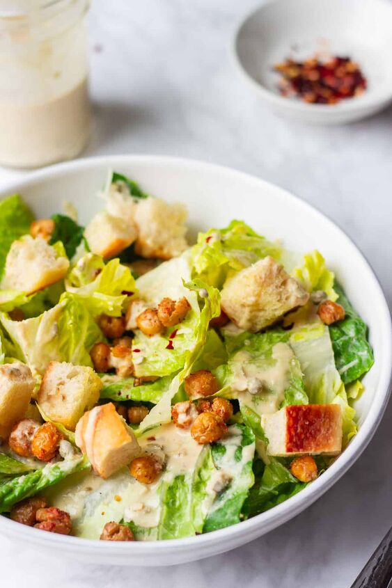 crowd pleasing vegan caesar salad you won t believe it s dairy free, Vegan Caesar Salad with crispy chickpeas and croutons in a white bowl on a white table