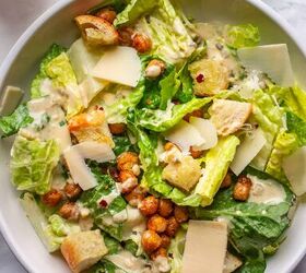 crowd pleasing vegan caesar salad you won t believe it s dairy free, A bowl of the best dairy free Caesar salad next to a small bowl with red pepper flakes and Tahini dressing