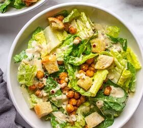 crowd pleasing vegan caesar salad you won t believe it s dairy free, Two bowls of creamy dairy free Caesar s salad on a white table with a grey napkin on a side