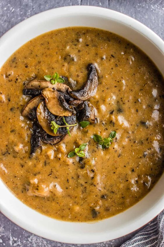 hearty vegan cream of mushroom soup with coconut milk, Overhead image of vegan cream of mushroom soup in a white bowl with a sprinkling of fresh thyme on top