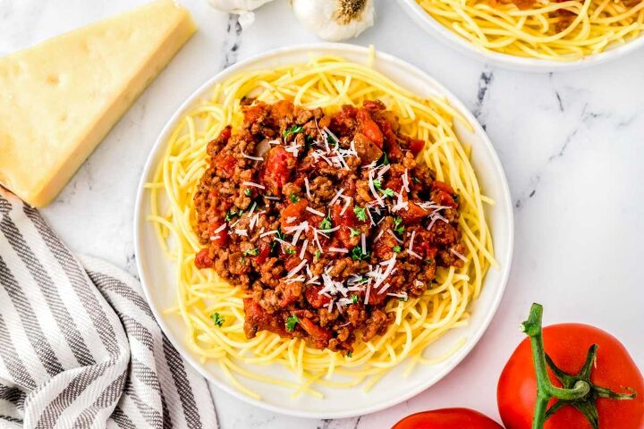 homemade spaghetti sauce with ground beef, A plate of homemade spaghetti sauce over pasta garnished with parmesan cheese