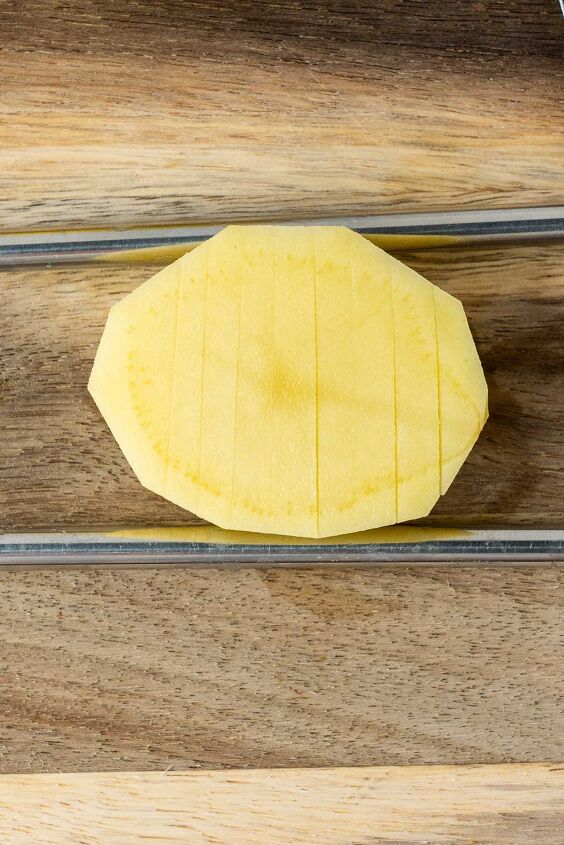 air fryer accordion potatoes, Place the potatoes on the cutting board with a chopstick on each side Slice partway down the potato letting the chopstick stop the knife from going all the way through the potato