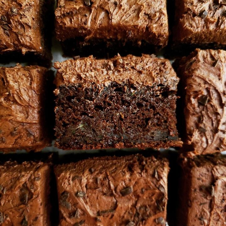 chocolate orange cake, chocolate zucchini sheet cake with chocolate buttercream frosting top down close up view of cake cut into 9 squares the center square is turned on its side so you can see the moist crumb and thick frosting layer