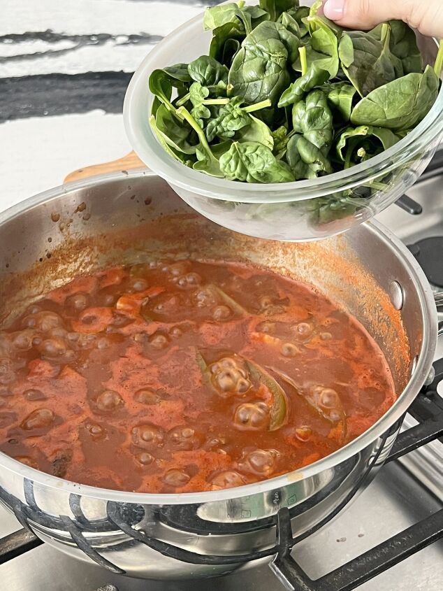 a healthy winter vegetable soup recipe, Pouring a bowl of fresh spinach into a simmering pot of healthy winter vegetable soup