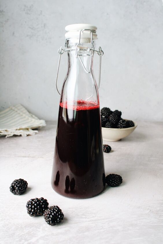 blackberry simple syrup, blackberry simple syrup in a glass bottle with blackberries scattered around