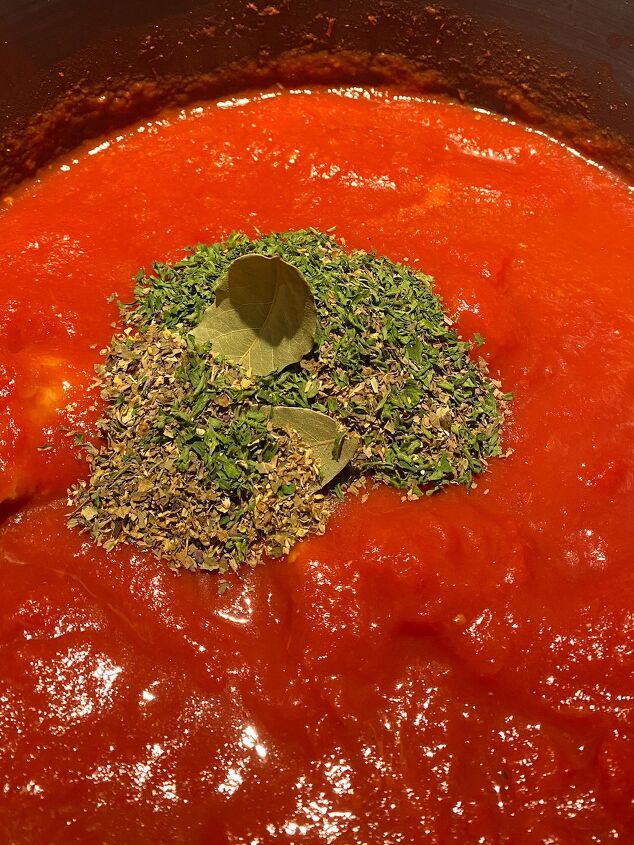the best traditional italian pasta sauce, photo of the spices on top of the tomato puree in a stock pot The making of traditional Italian pasta sauce
