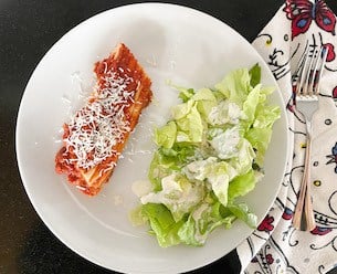 the best traditional italian pasta sauce, white plate with cheesy manicotti and a side salad