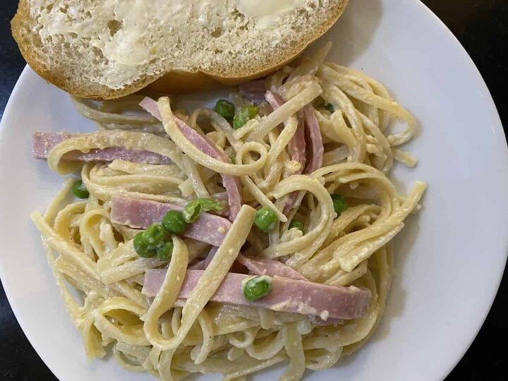 the best traditional italian pasta sauce, lazy day ham pea pasta recipe plated on a white plate with a slice of French buttered bread