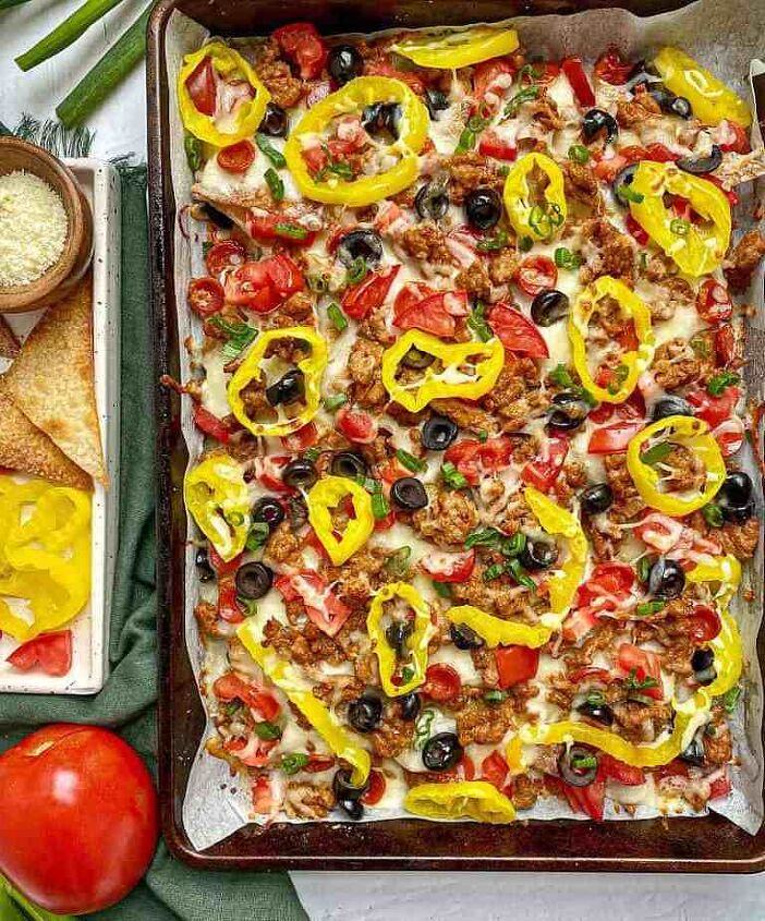 italian nachos happy honey kitchen, Italian Nachos on a sheet pan topped with sausage alfredo sauce cheese tomatoes olives and peppers A tray with extra toppings and grated cheese is next to the pan