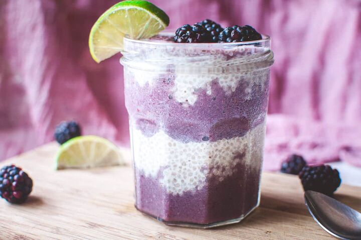 blackberry lime chia seed wellness parfait, a clear glass filling with chia seed pudding and purple smoothie