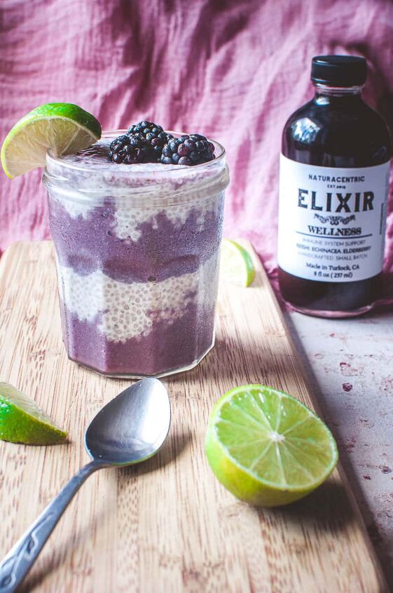 blackberry lime chia seed wellness parfait, a frosty glass of chia seed parfait alongside a bottle of naturacentric wellness elixir