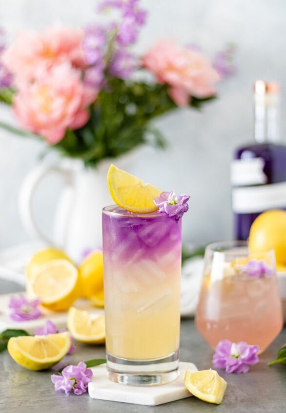 honey lavender gin lemonade with empress, Two glasses of Empress Gin Lemonade surrounded by fresh lemons flowers and a bottle of Empress 1908 Gin
