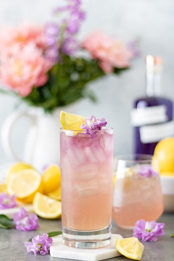 honey lavender gin lemonade with empress, Two glasses of Empress Gin Lemonade surrounded by fresh lemons flowers and a bottle of Empress 1908 Gin