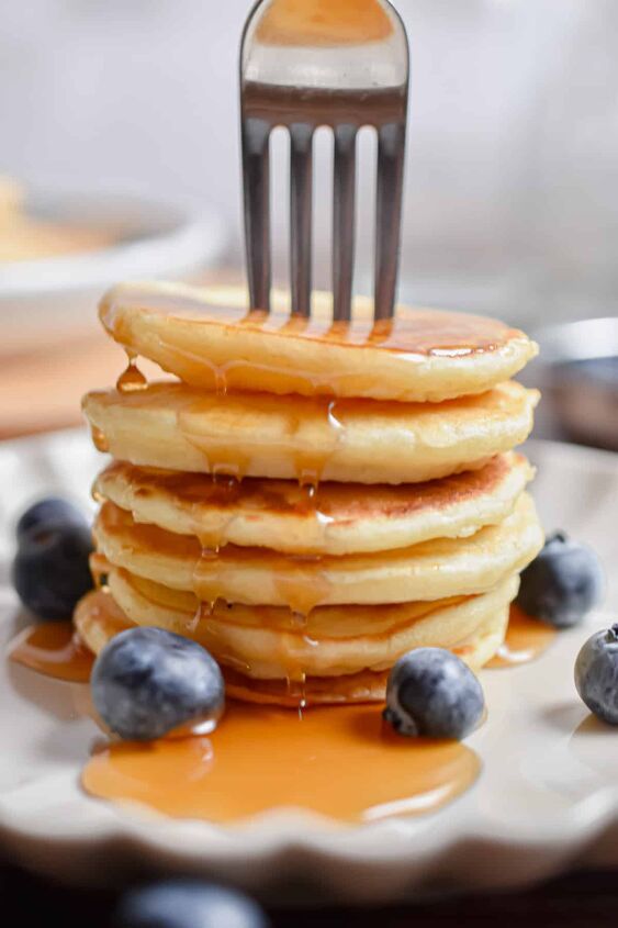 silver dollar pancakes mini pancakes, A fork is in a stack of silver dollar pancakes with maple syrup