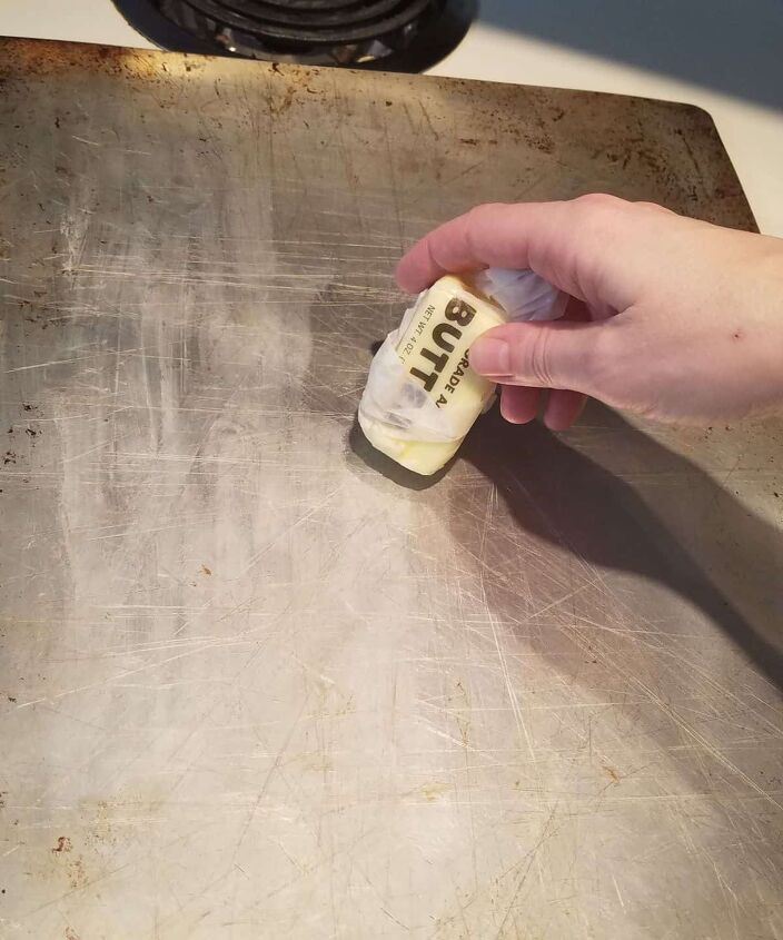 the easiest ever patriotic cinnamon roll star, butter being spread on a baking sheet