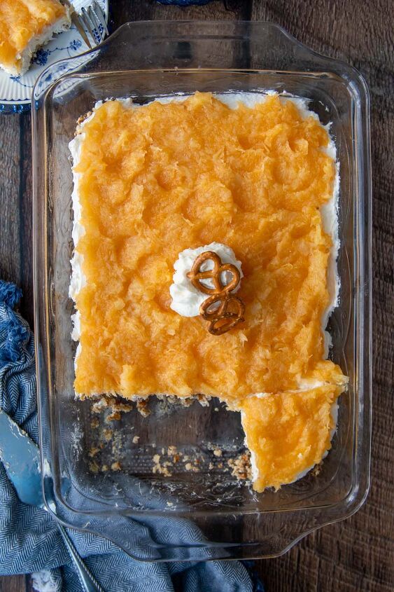 pineapple pretzel salad, overhead shot of pineapple pretzel salad in a glass dish with a blue towel next to it