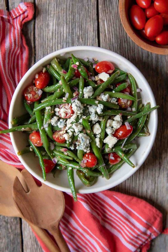 marinated green bean salad, overhead of green bean salad in a white bowl with a red towel and serving tongs