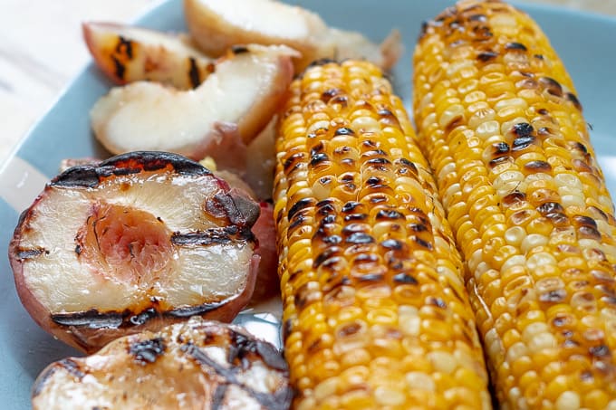 grilled chicken salad, grilled peaches and corn on a blue plate