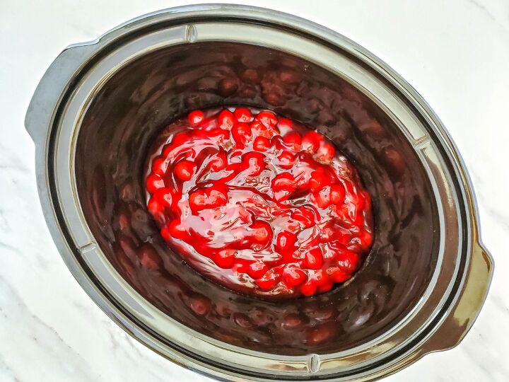 chocolate dump cake with cherries, cherry pie filling in bottom of black slow cooker