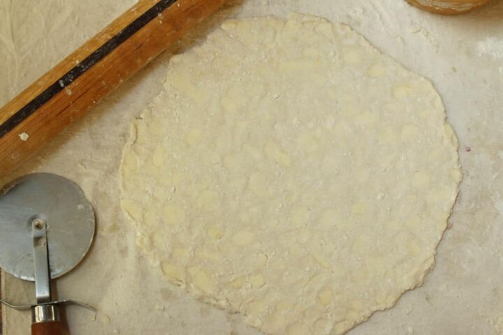 butterhorn recipe with cottage cheese, A rolled circle of pastry dough with a pizza cutter next to it