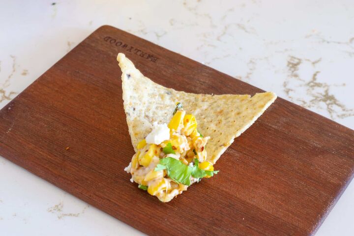 elote dip recipe, Elote dip on tortilla chip on a wooden plate