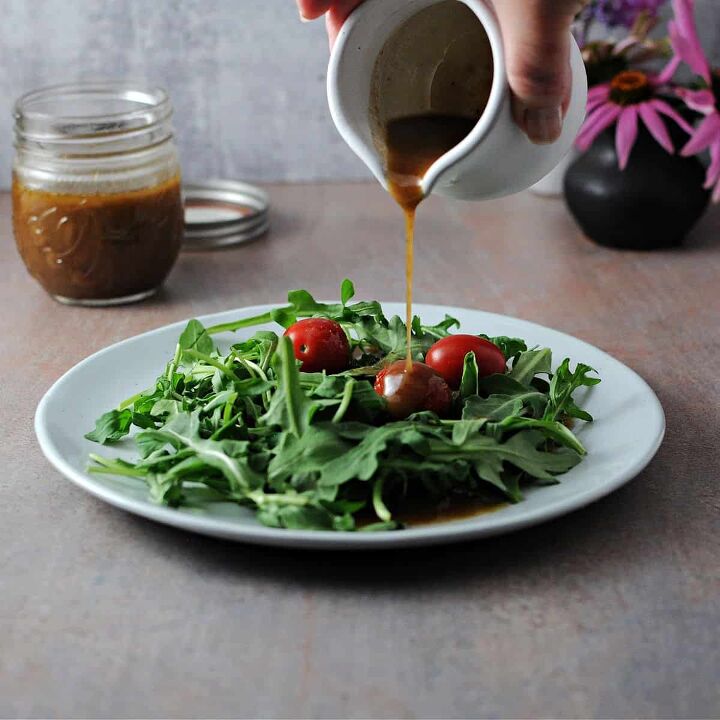 balsamic vinaigrette, small pitcher pouring balsamic vinaigrette onto a plate of salad greens