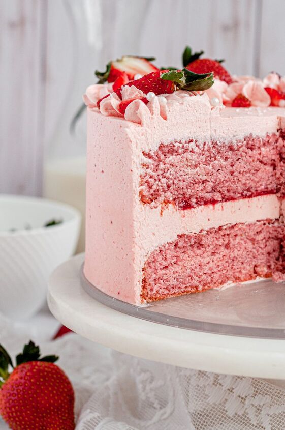 gluten free strawberry cake dairy free, A light pink strawberry layer cake covered in pink frosting and topped with bright red fresh strawberries There are several slices out out of the cake allowing you to see the inside of the cake