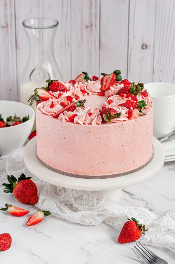 gluten free strawberry cake dairy free, A light pink strawberry layer cake covered in pink frosting and topped with bright red fresh strawberries