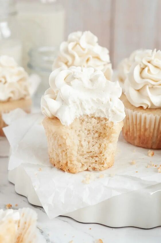 gluten free vanilla cupcakes dairy free, Light golden vanilla cupcakes topped with ruffled white vanilla frosting The cupcake in the front has a bite taken out of it