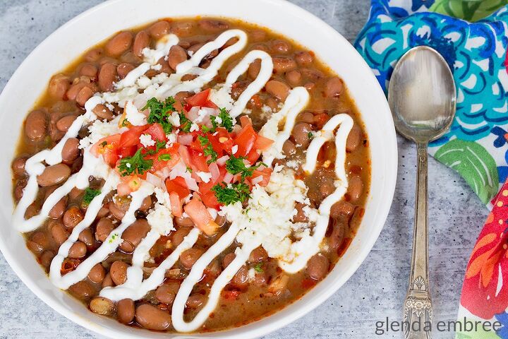 slow cooker pork carnitas, Slow Cooker Charro Beans in a white ceramic bowl and garnished with sour cream diced tomatoes green onion parsley and queso fresco