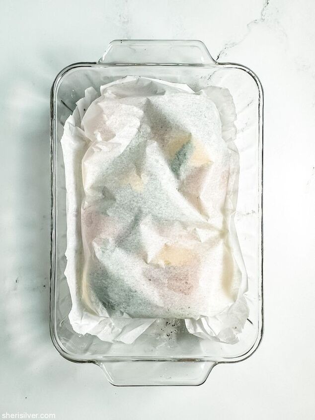 perfect oven baked chicken breasts, chicken breasts in a glass baking dish covered with parchment paper