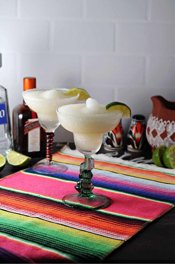 2 frozen margaritas on a bright striped table runner