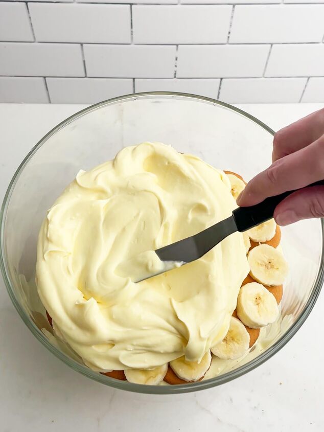 how to make easy banana pudding, hand spreading pudding mixture into trifle dish