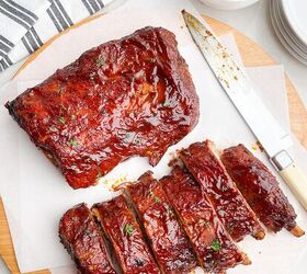 dr pepper crock pot ribs, two half racks of ribs on white parchment paper on a wooden cutting board next to a knife
