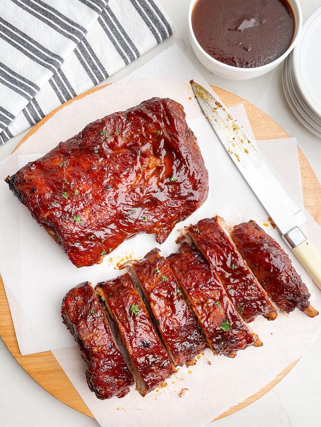 dr pepper crock pot ribs, two half racks of ribs on white parchment paper on a wooden cutting board next to a knife