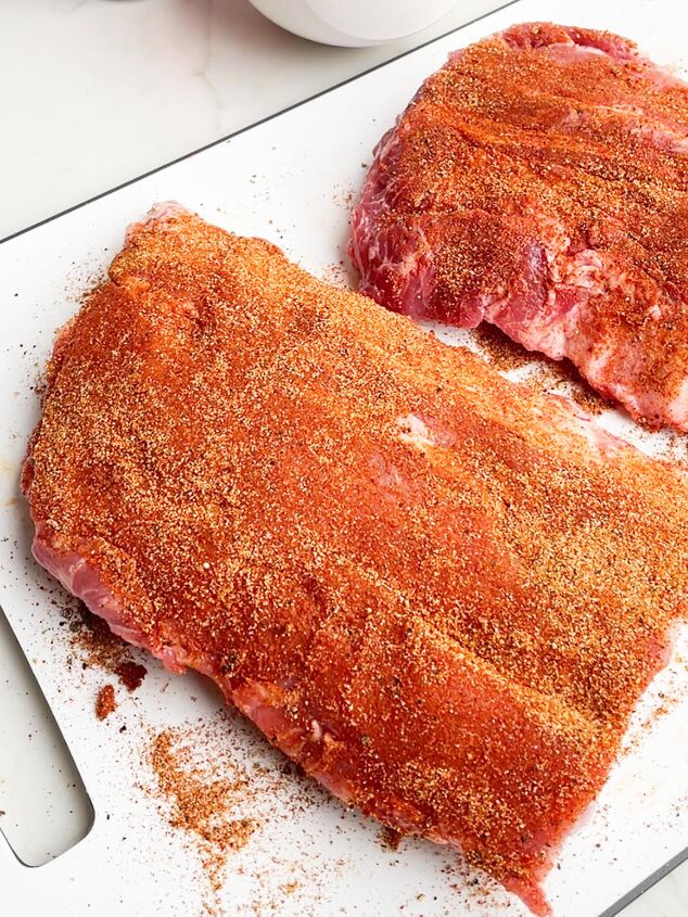 dr pepper crock pot ribs, two half racks of ribs with dry rub on a white cutting board