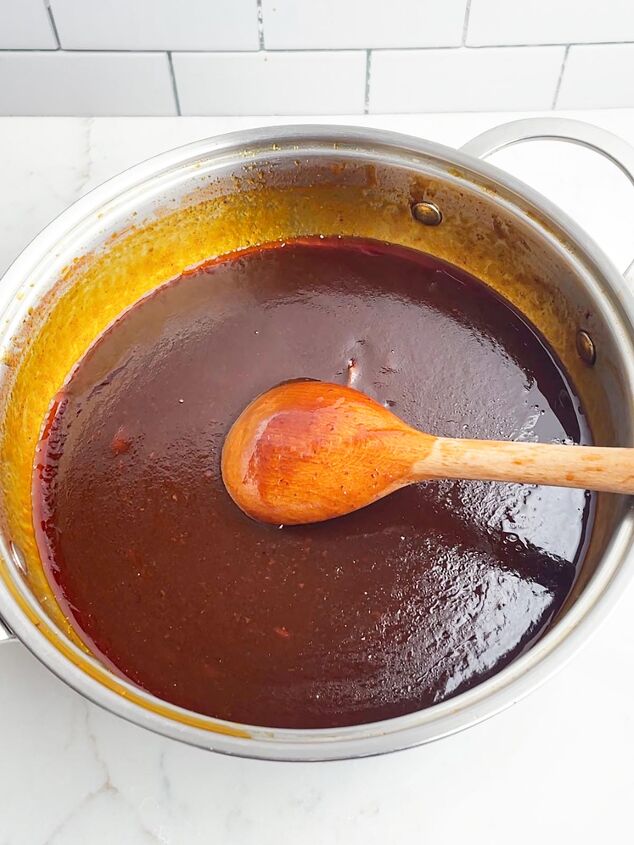 dr pepper crock pot ribs, large skillet with Dr Pepper BBQ sauce and a wooden spoon