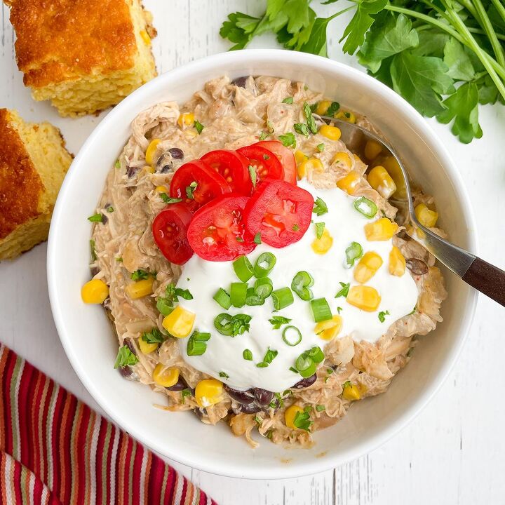 dr pepper crock pot ribs, cream cheese chicken chili in a white bowl with cornbread and parsley on a white countertop