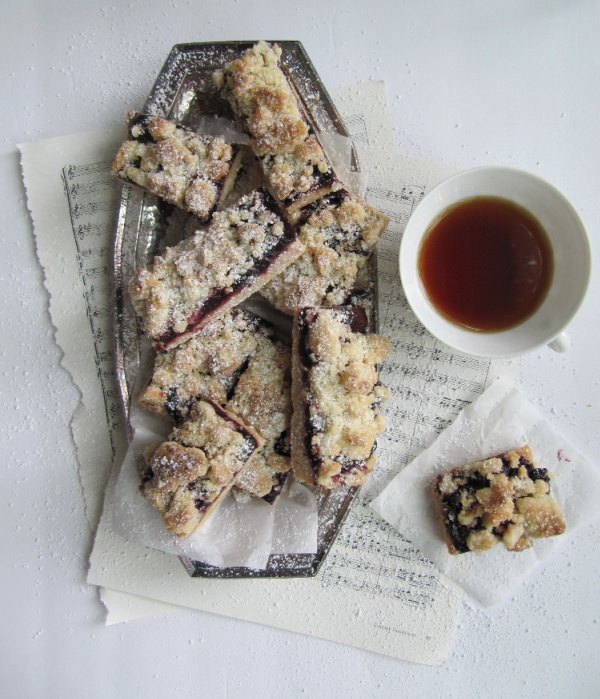 roasted cherry streusel shortbread cookie bars, roasted cherry streusel bars in a silver tray sitting on sheet music with a cup of tea in a white cup
