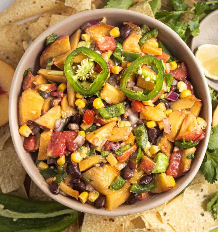 jalapeno peach salsa, Jalapeno Peach Salsa in a pink bowl with all ingredients shower and chips and cilantro on the side outlining the shape of the bowl