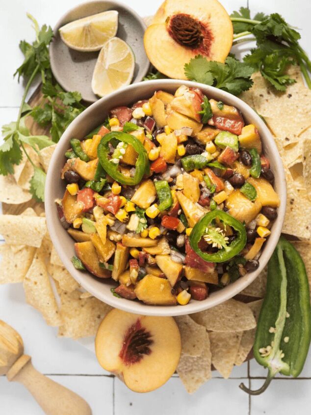 jalapeno peach salsa, Jalapeno Peach Salsa in a pink bowl with all ingredients showing and chips are on the outside of the bowl