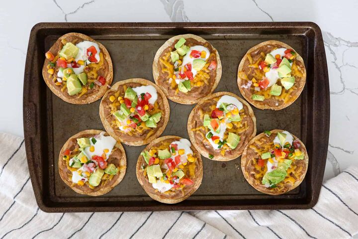 Tostada shells covered in refried beans cheese sour cream diced avocado and salsa