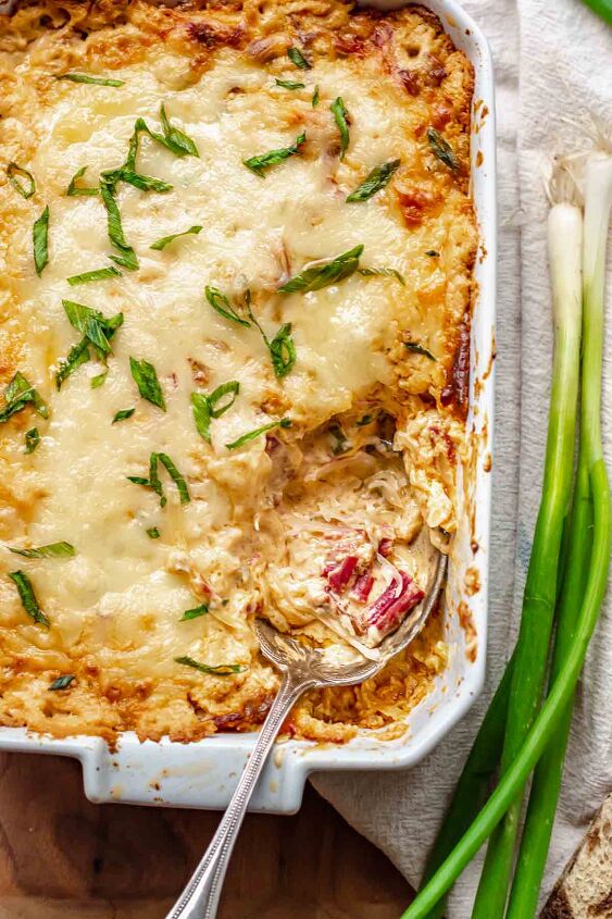 hot corned beef reuben dip, A spoon rests in a casserole dish with dip on it