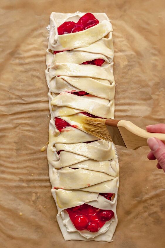 cream cheese cherry danish with puff pastry, A brush adds egg wash on top of the assembled danish