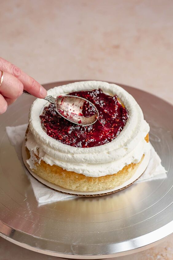 raspberry and almond cake, A spoon smooths raspberry jam into the center of the cake