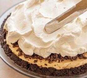 oreo peanut butter pie, An offset spatula spreads whipped cream on top of the pie